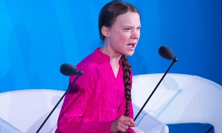 Greta Thunberg sitting in a pink top during a speech at the UN.