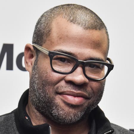 Jordan Peele, wearing glasses, looking at the camera.