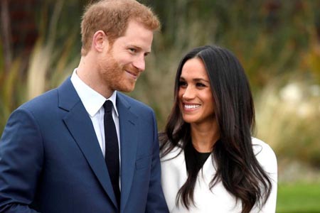 Meghan Markle and Prince Harry holding hands and smiling together.