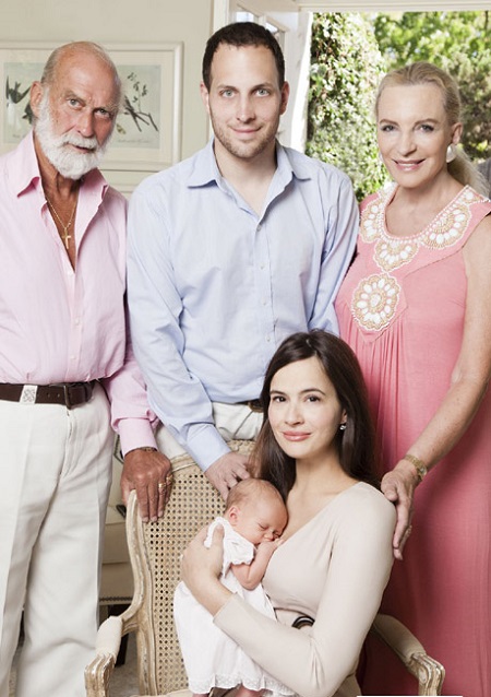 Sophie sitting in a chair with her first toddler when she was a baby. He husband (middle) and his parents standing behind him.