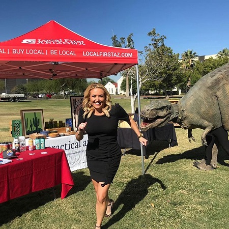 Jaime in a running pose while smiling with a T-Rex statue beside her.