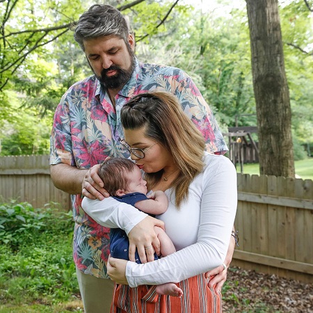 Portwood kissing James on the forehead as Glennon holds them from the back looking at the baby.