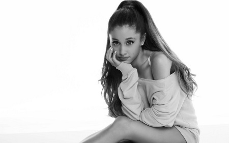 Ariana Grande's Black and White photo with her hand resting on her chin while sitting on the floor.