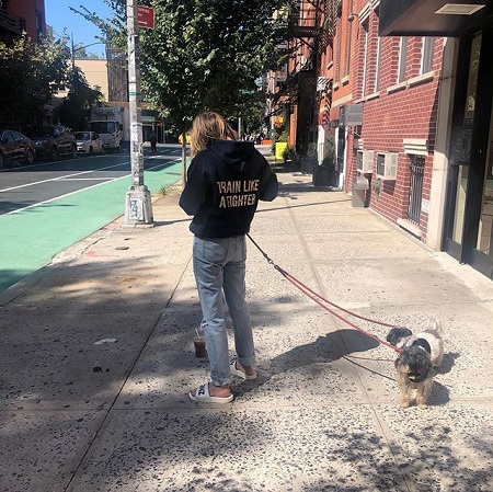 Ashley Benson outdoor facing the back with her two dogs with leashes.