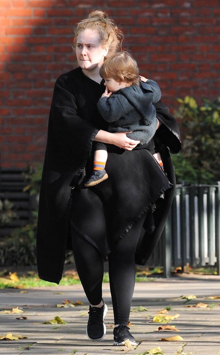 Adele in black carrying her son Angelo in 2015.