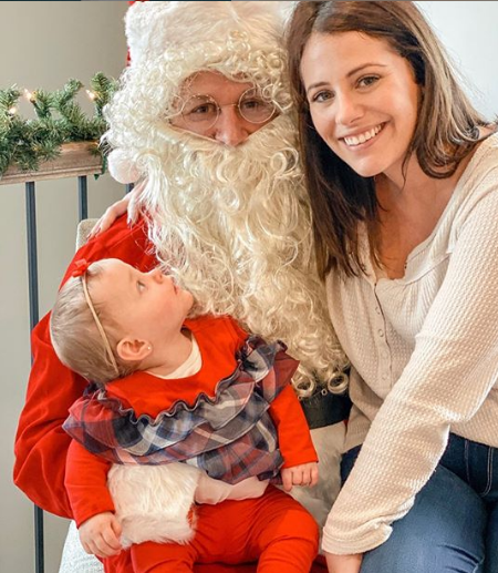 Baby Mila sits on her father's lap, while Anthony is dressed up as Santa.