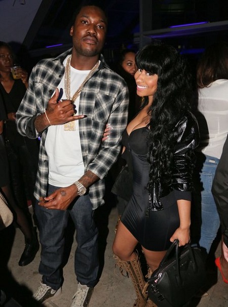 Nicki Minaj holding on to Meek Mill's hand with his other hand a signature of hip-hop.