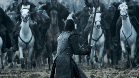 Jon Snow stands alone in a field against the Bolton army, with his sword drawn and ready to fight.