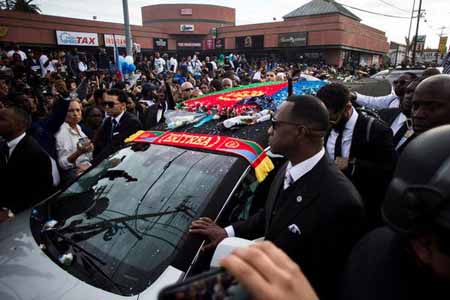 A hearse covered in flags, carries Nipsey Hussle to his funeral.