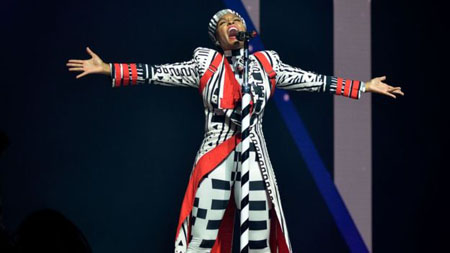 Jenelle Monae lifts her arms to the side as she performs at this year's Glastonbury.