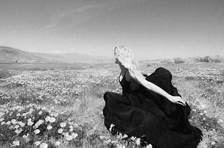 Lili Reinhart in a black and white photo running in a flower garden.