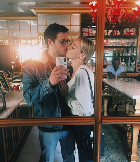 Rachel Skarsten and Alexandre Robicquet taking a selfie while kissing in a coffee shop.