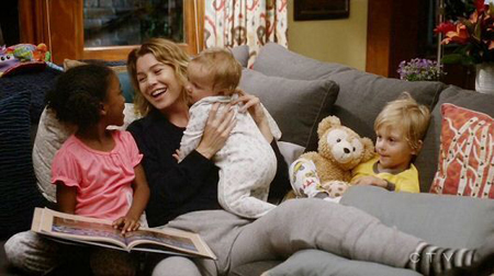 Meredith Grey with all of her children siting on a couch.