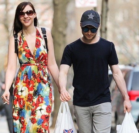 erin darke daniel radcliffe walking on the street with shopping bags on their hands.